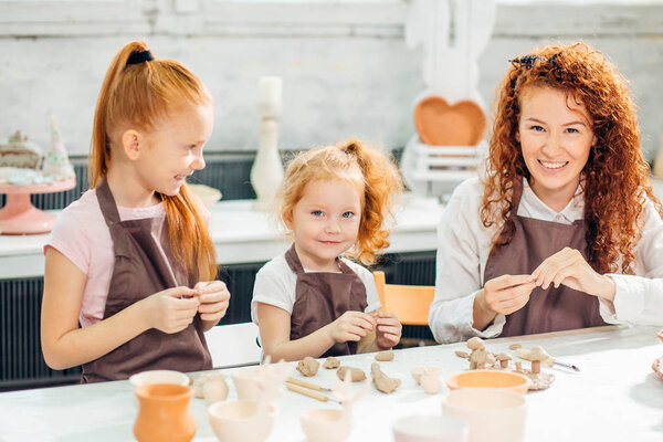 redhead mother and two daughter mold with clay, pottery children