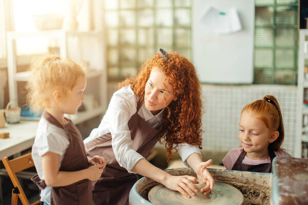 mother and two redhead daughters made clay cup with pottery wheel