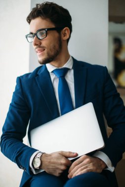 Ofiste dizüstü bilgisayarla çalışan yakışıklı iş adamı.