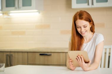 Dijital tablet ile oturan mutlu gülümseyen kadın