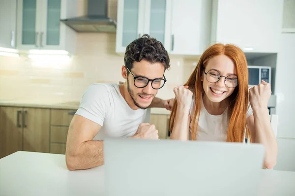 Verbaasd paar met open mond op lijn met laptop in de woonkamer in huis — Stockfoto