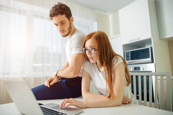 Shoked paar met open mond op lijn met laptop in de woonkamer in huis — Stockfoto