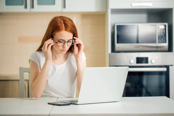 Femeie de afaceri roșcată concentrată care lucrează pe laptop într-un birou modern luminos — Fotografie, imagine de stoc