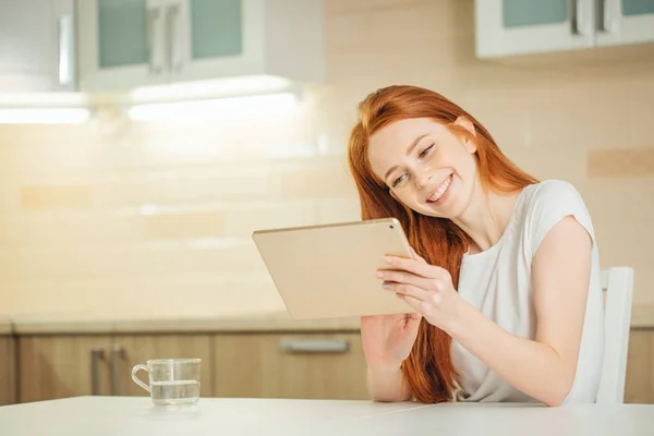 Счастливая улыбающаяся женщина, сидящая с цифровым планшетом — стоковое фото