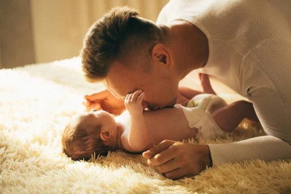 Padre sdraiato sul letto e tiene il suo bambino — Foto Stock