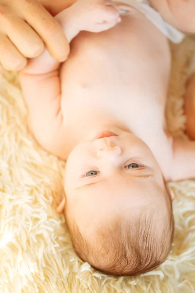 Újszülött fekve mosolyogva nézi a kamera, míg apa fogta a fejét — Stock Fotó