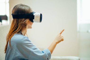 onun Vr kulaklık ayarlama ve halı üzerinde evde otururken gülümseyen kadın