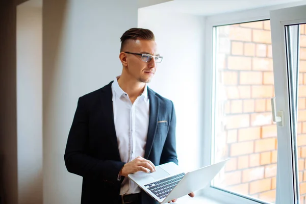Hombre guapo con gafas de trabajo con el ordenador portátil en la oficina — Foto de Stock