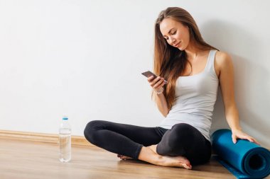 Yoga yaparken ve cep telefonuyla katta oturan kadın