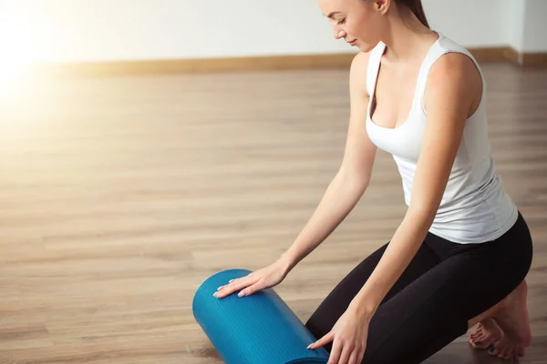 Mujer practicando yoga, preparándose para el ejercicio, desenrollando o rodando estera de yoga —  Fotos de Stock