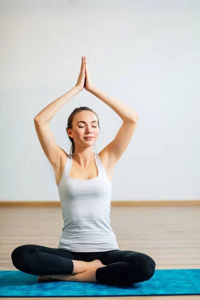 Mujer joven medita mientras practica yoga en sala de entrenamiento — Foto de Stock