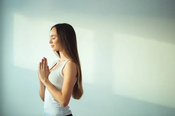 Женщина практикует йогу и медитацию, держит ладони вместе в мудре намасте — стоковое фото