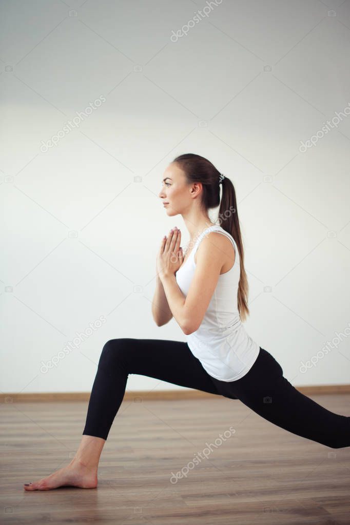 woman practicing yoga, standing in Warrior one exercise, Virabhadrasana