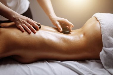 genç kadın sıcak taş spa salonunda masaj.