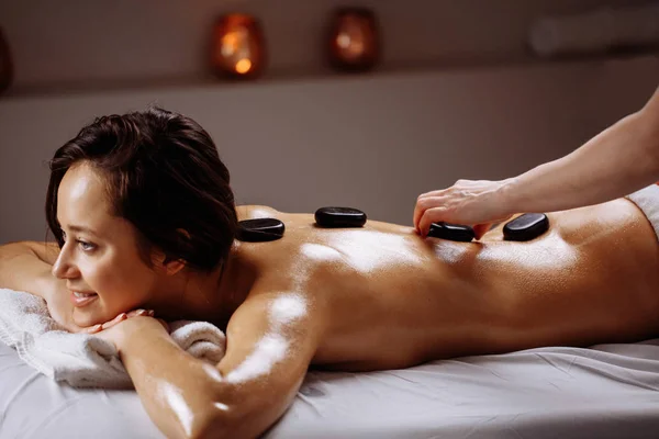 温泉サロンで熱い石マッサージを受ける女性。美容治療のコンセプト — ストック写真