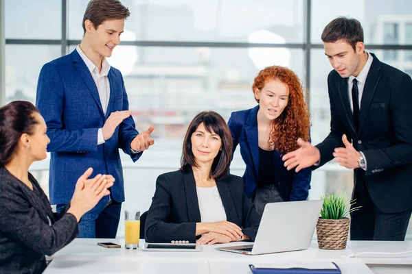 Mannelijke en vrouwelijke zakenmensen rond laptopcomputer in kantoor — Stockfoto