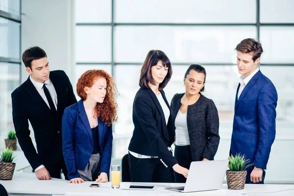 Hombres y mujeres de negocios alrededor de computadoras portátiles en la oficina — Foto de Stock