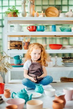 birçok fincanla kil atölye stüdyoda oturan Kızıl saçlı kız