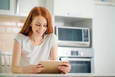 Dijital tablet ile oturan mutlu gülümseyen kadın