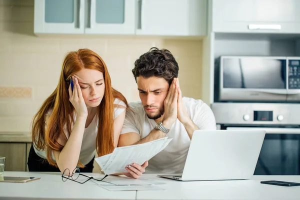 Casal preocupado pagando suas contas online com laptop em casa na sala de estar — Fotografia de Stock