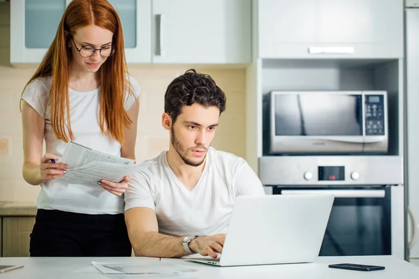 Woman calculate or write accounts with pen, her husband using laptop — Stock Photo, Image