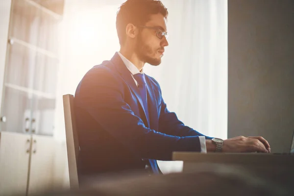 Knappe zakenman werkt met laptop op kantoor — Stockfoto