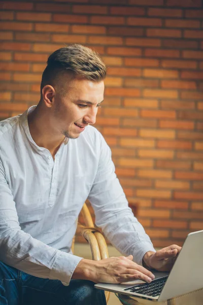 Człowiek siedzi w domu i pracy na laptopie. mężczyzna pracy z domowego biura loft — Zdjęcie stockowe