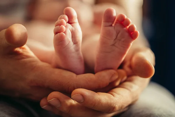 Nyfödd baby ben i mödrar härlig hand med mjukt fokus på spädbarn fot — Stockfoto