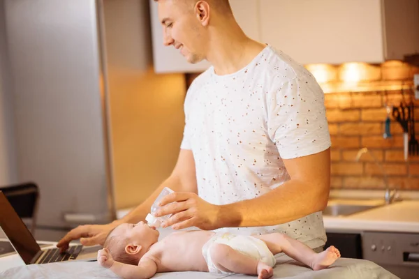 Папа пытается работать, стоя со своей новорожденной малышкой в домашнем офисе — стоковое фото