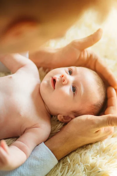 Nyfödda barnet liggande leende tittar kameran medan far håller hans huvud — Stockfoto