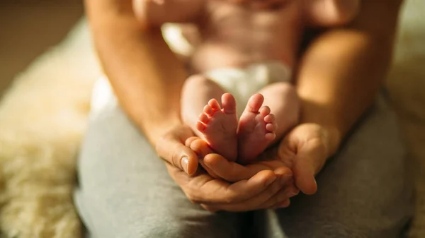 Padres sosteniendo en las manos los pies del bebé recién nacido Imagen De Stock