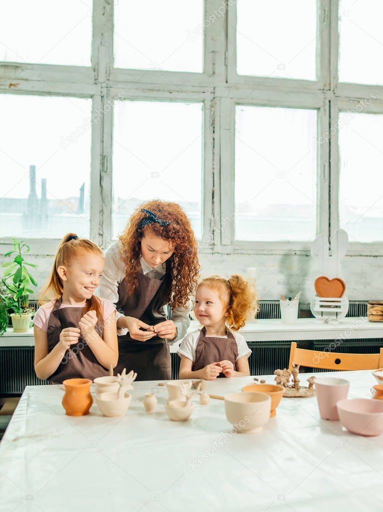 redhead mother and two daughter mold with clay, pottery children