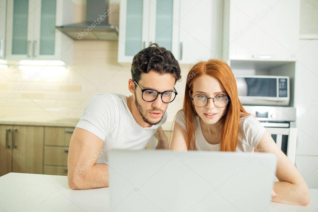 couple browsing internet together sitting at table and smiling and read screen