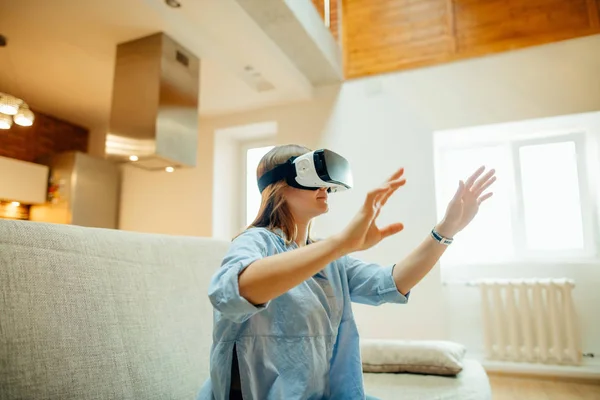 Mujer ajustando sus auriculares VR y sonriendo mientras está sentada en la alfombra en casa — Foto de Stock