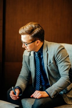 adam görüşme için hazırlanıyor. O takım, iskemle, salonda oturmuş bekliyor