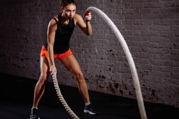 Mujer atlética haciendo ejercicios de cuerda de batalla en el gimnasio — Foto de Stock