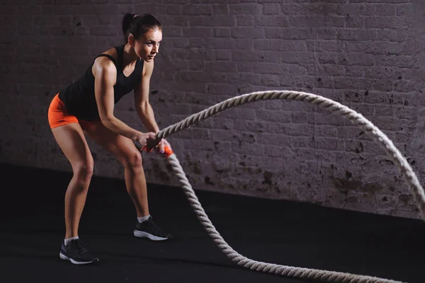 Mulher treinando com corda de batalha em cross fit ginásio — Fotografia de Stock