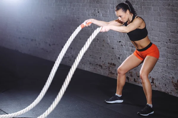 Mujer atlética haciendo ejercicios de cuerda de batalla en el gimnasio — Foto de Stock