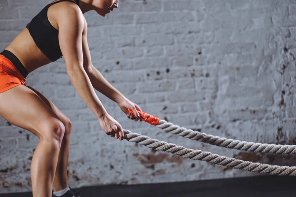 De cerca foto de la mujer atlética haciendo ejercicios de cuerda de batalla en el gimnasio — Foto de Stock