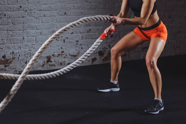 Mujer poderosa hacer ejercicio con cuerdas de batalla en el gimnasio —  Fotos de Stock