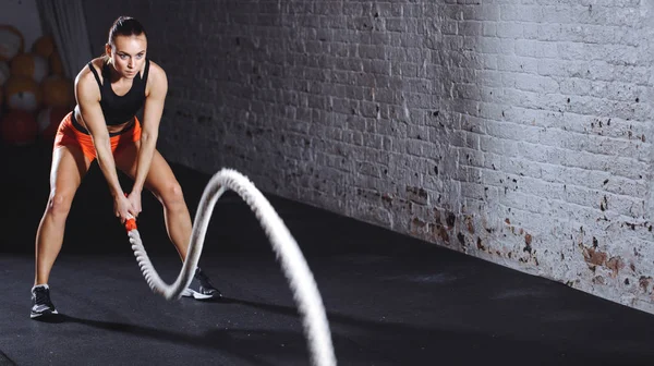 Mujer haciendo ejercicio de cross fit con una cuerda de batalla —  Fotos de Stock