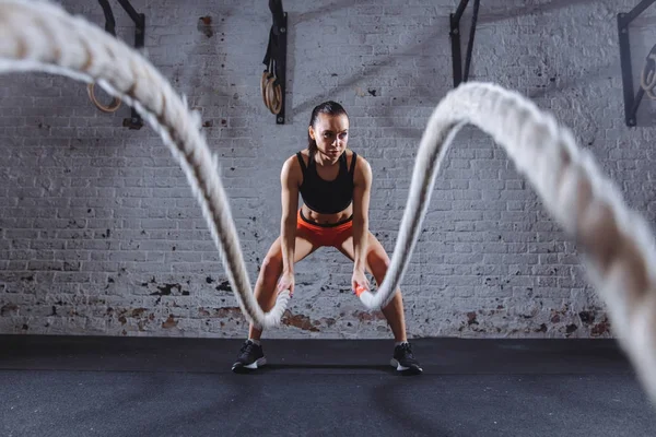 Fiatal nő dolgozzanak ki a csata kötelek cross fit tornaterem — Stock Fotó