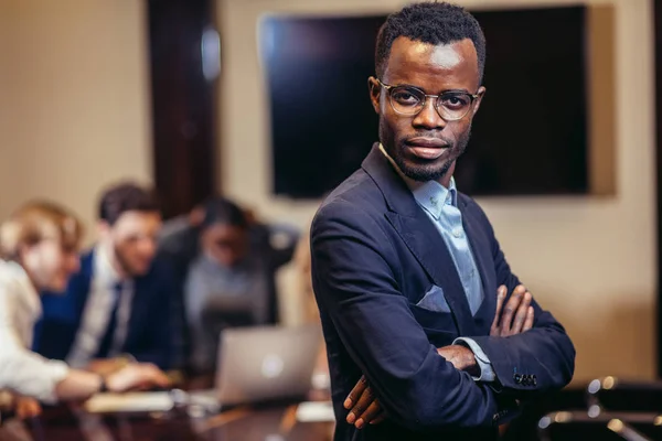 Africano uomo d'affari guardando sulla macchina fotografica con gruppo di uomini d'affari su sfondo — Foto Stock