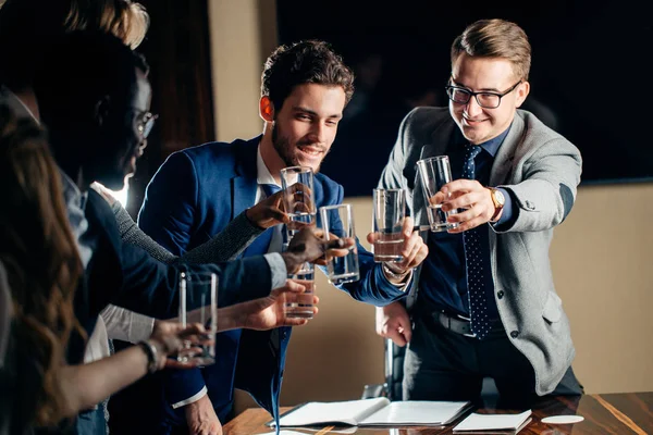 Podnikatelé řinčí poháry a usmívající se přitom slaví v jednání — Stock fotografie