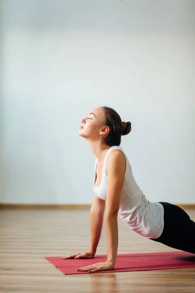 Mujer practicando yoga en interiores. Hermosa chica práctica cobra asana en clase —  Fotos de Stock