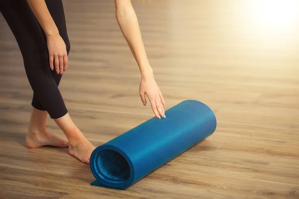 Mulher praticando ioga, preparando-se para o exercício, desenrolando ou rolando tapete de ioga — Fotografia de Stock