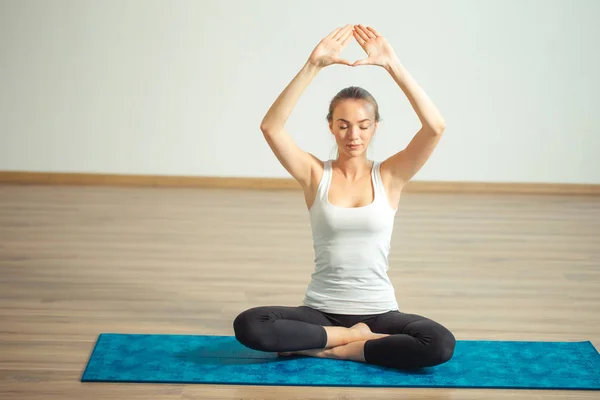 Jovem mulher medita enquanto pratica ioga no salão de treinamento — Fotografia de Stock