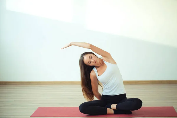 Jeune fille mince fait de l'exercice d'aérobic assis dans la pose de lotus sur le tapis — Photo