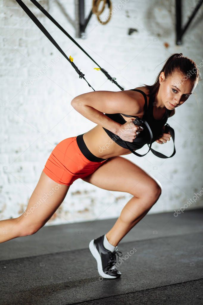 Trx concept. lady exercising her muscles with help of suspension trainer sling