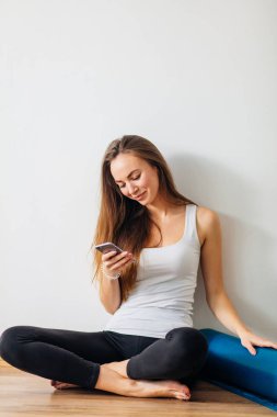 Yoga yaparken ve cep telefonuyla katta oturan kadın